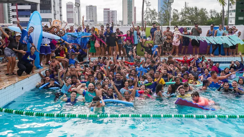 Grupo de crianças e voluntários na piscina durante a Colônia de Férias
